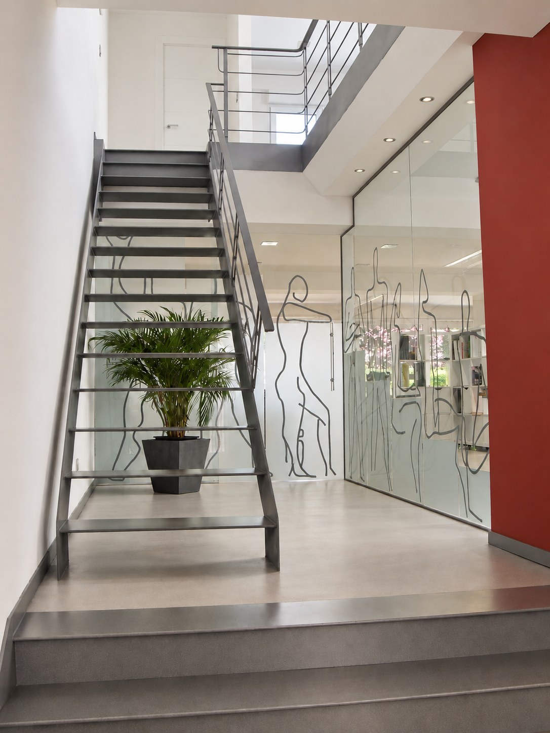 Escalera metálica del estudio ERD Arquitectos junto a mamparas de vidrio